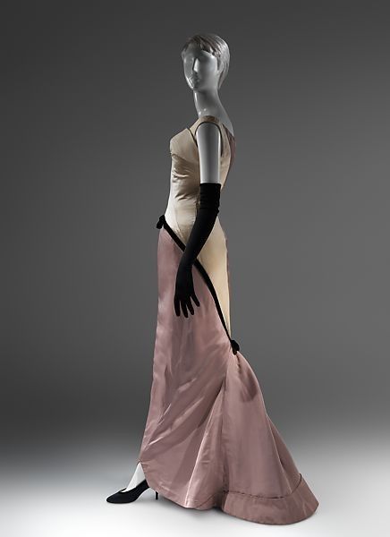 a mannequin is displayed wearing a formal gown and long gloves. the dress is primarily a pale champagne color on the front and transitions to a mauve or dusty rose shade from the hips down and along the back. it has a black trim along the side. the mannequin also has black high heel shoes on.
