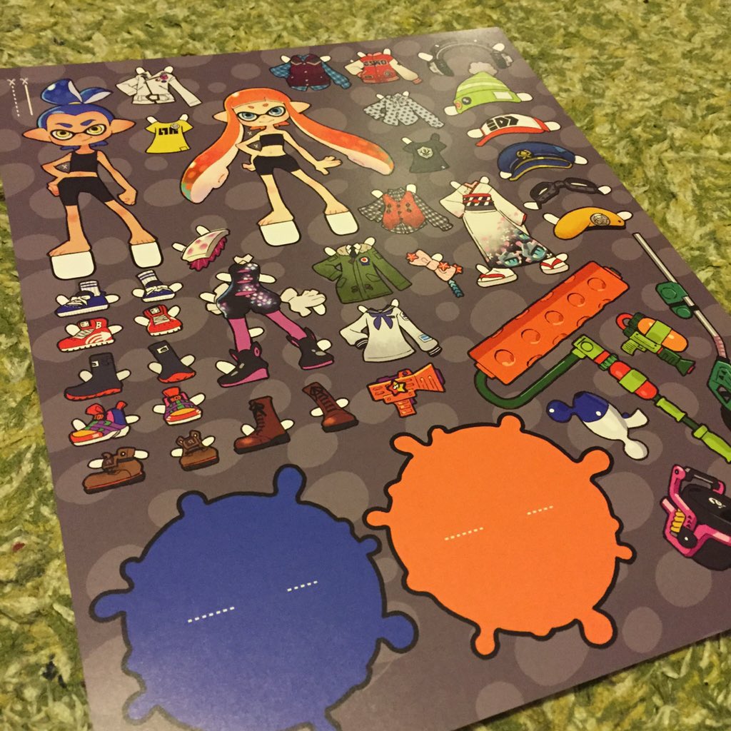 a photograph of a splatoonthemed paper doll set. the set features two characters, an orange inkling girl and a blue inkling girl, with a variety of clothes, shoes, hats, and weapons for them to wear. the set is arranged on a gray background with orange and blue ink splatters.