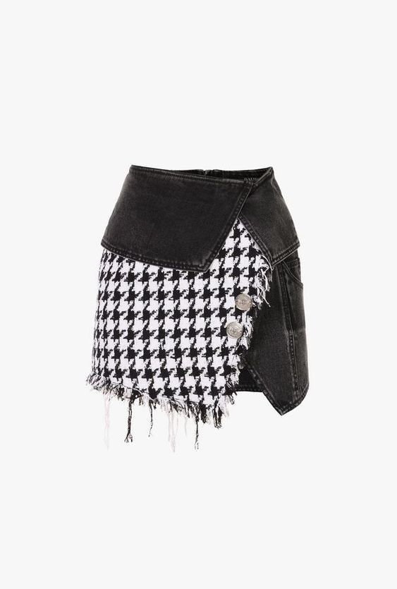 an asymmetrical denim skirt featuring a houndstooth pattern with frayed edges, a black denim panel, and button detailing.
