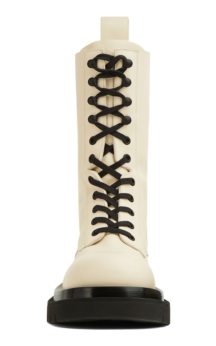 he image shows a pair of creamcolored, laceup platform boots. the boots are made of leather and have a chunky sole. the laces are black. the boots are shown from the front and are slightly angled.
