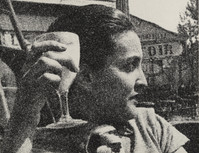 a black and white, closeup photograph of a woman outdoors, holding a stemmed glass to her lips. she appears to be casually dressed and is in a thoughtful, pensive mood. the background is blurry and shows a street scene with buildings and trees. the image has a grainy, lowresolution quality characteristic of vintage photographs.  the overall impression is one of a candid moment captured from a historical period, possibly the mid20th century.