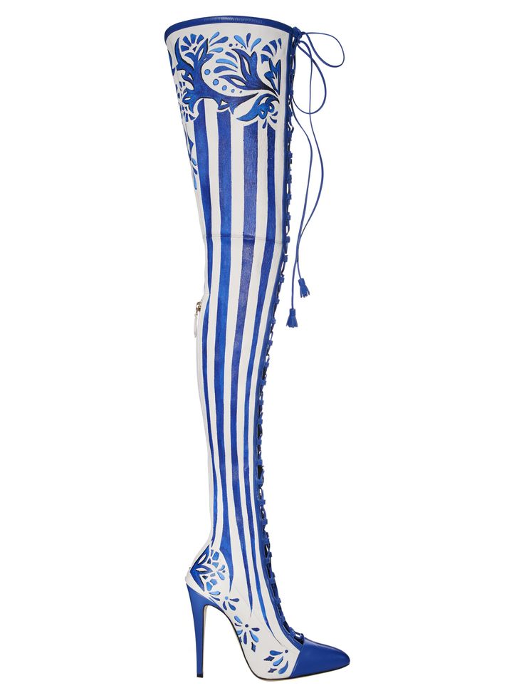 a single thigh high boot stands upright against a white background. the boot is primarily white with vertical blue stripes running down its length. the toe of the boot and the heel are solid blue, decorated with a floral pattern in white. at the top of the boot, a blue floral design adorns the front. long blue laces run up the side of the boot.