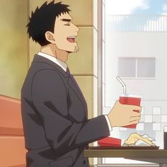 a man in a suit is sitting down and laughing while holding a drink in a fast food restaurant. he appears to be enjoying himself and is likely on a break.  the image is brightly lit with a warm, inviting atmosphere.