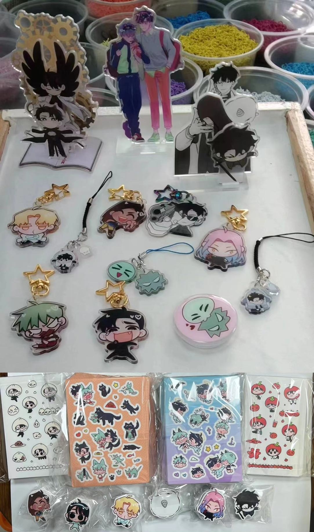 this image shows a collection of anime and manga character figurines, keychains, charms, and stickers. they are displayed on a white desk, with a variety of colors, designs and characters featured. the figurines are mostly in anime style, with large eyes and expressive features. the keychains and charms are also colorful and playful, featuring a variety of characters. the stickers are arranged in rows and feature cartoon images of various characters. the overall impression is one of fun and whimsicality. the image is likely to appeal to fans of anime and manga, and it could be used as a promotional image for a store or website that sells these types of items.