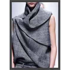 a woman is posing for the camera while wearing a grey, sleeveless sweater with a scarf that is wrapped around her neck and draped over her shoulders. the scarf is in multiple folds and has a very textured appearance.  she is posing for a portrait photo.