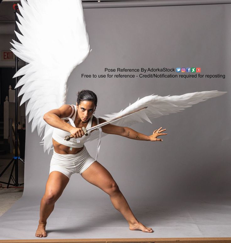 a woman with white angel wings is holding a sword in a fighting stance. she is dressed in a white outfit and is posed in a dynamic position. she is looking at the camera with a determined expression. this is a reference photo for artists.