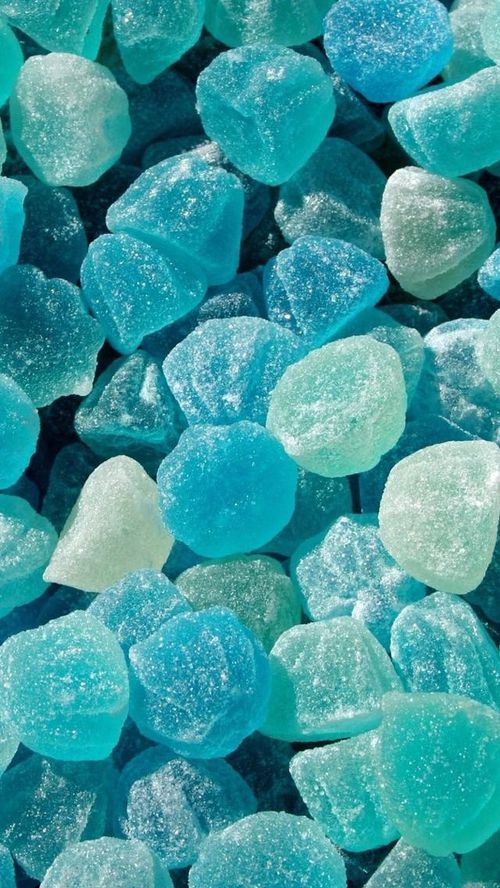 a closeup image of blue and turquoise jelly candies with a soft, pillowy texture. the candies are piled high, creating a vibrant and visually appealing backdrop. their translucent nature reveals a subtle, almost ethereal quality. the image captures the essence of sugary treats and evokes a sense of sweetness and indulgence.