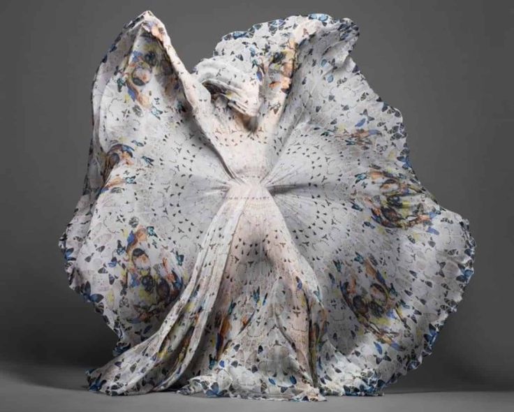 a model is wearing a beautiful white dress covered in blue butterflies. the dress is flowing and dramatic, and the model's pose is graceful. the image is artfully shot, and the lighting is soft and ethereal. the overall effect is beautiful and mysterious.