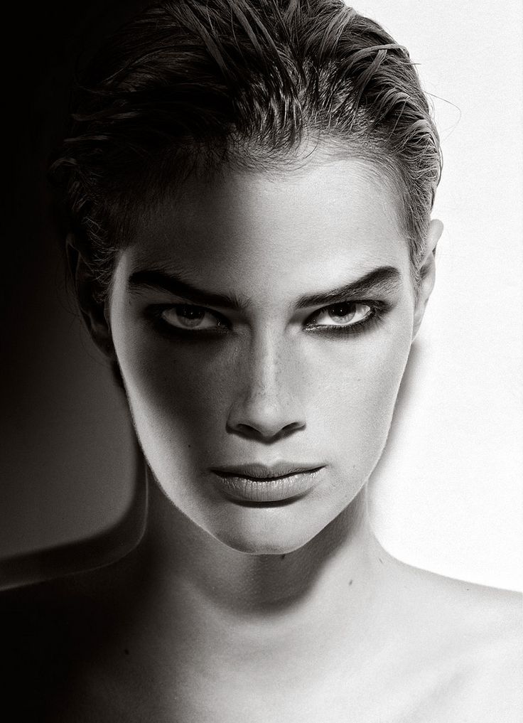 a black and white portrait of a woman looking intently at the camera. her hair is slicked back, and her eyes are intensely focused. the lighting is dramatic, with strong shadows on her face. her makeup is dramatic and creates a striking contrast. the image conveys a sense of intensity and emotion.