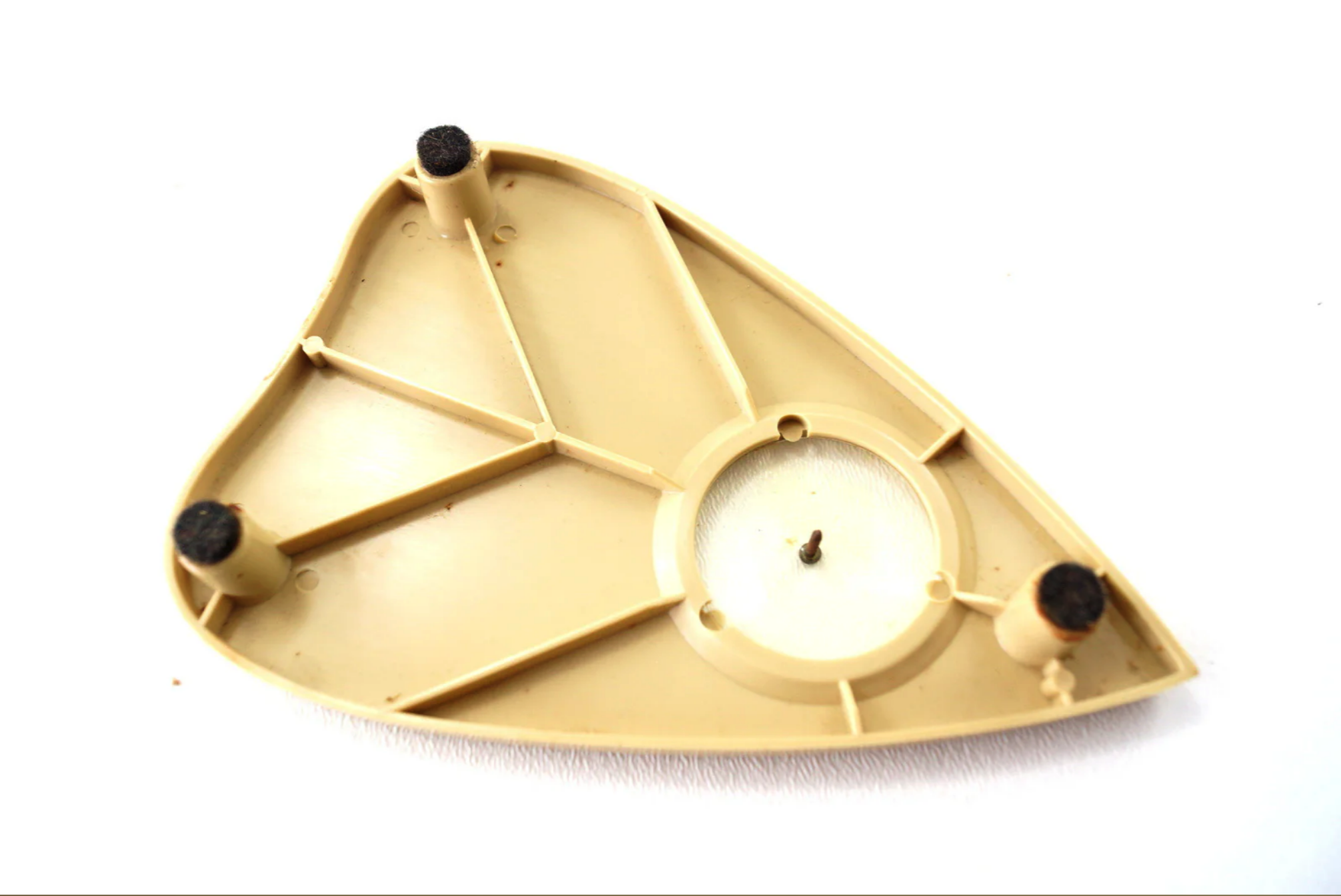 a beige turntable base, likely from a vintage or retro record player. it features three rubber feet, a circular platter opening, and a visible screw in the center. the base is shaped like a long triangle.
