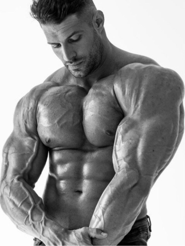 a muscular man stands in a studio with his arms flexed, showcasing his defined biceps, triceps, and chest. the image is in black and white, creating a dramatic and powerful atmosphere.  the man's veins are visible, highlighting his intense training and dedication to fitness.  the strong lines of his musculature, the textured skin, and the intense look in his eyes all contribute to the image's impact.  the image is likely intended to inspire and motivate viewers with its depiction of human strength and potential.