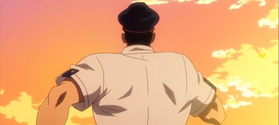 a man with dark hair wearing a white shortsleeved collared shirt with dark accents and a dark hat is standing with his back to the camera and looking into the distance at a vibrant sunset. the sky is a mix of orange, yellow, and white clouds.