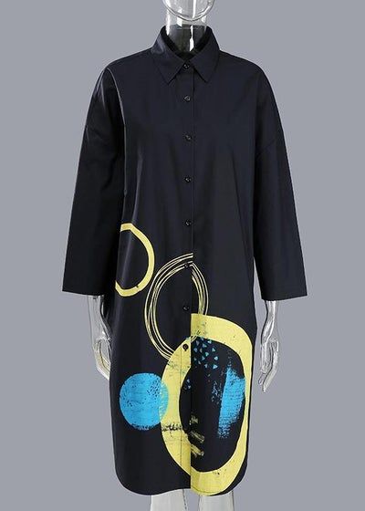 a black shirt dress with a collar and long sleeves is displayed on a mannequin. the dress features an abstract print with yellow, blue, and white circular designs on the lower part of the dress.