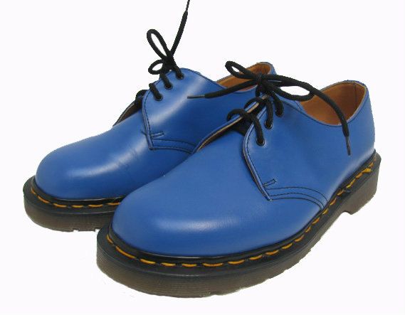 a pair of dr. martens 1461 shoes are displayed on a white background. they are crafted from smooth, blue leather and feature black laces and black soles with signature yellow stitching along the welt.