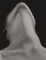 the image is a closeup, black and white photograph of a person's nude torso and neck. the focus is soft and blurred, creating an abstract effect that emphasizes the curves and shapes of the body rather than sharp details. the background is dark, drawing attention to the lighter tones of the skin. the subject's head is tilted back, and the overall impression is one of sensuality and artistic expression, leaving much to the viewer's interpretation. the style is minimalist, emphasizing the fundamental forms of the human body.