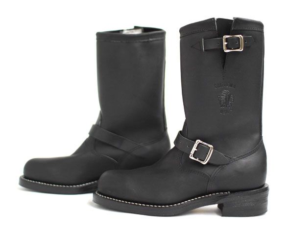 two black leather boots are shown, one on the left is slightly out of focus and on the right is in focus.  both boots are engineer boots, with buckles and a short heel.