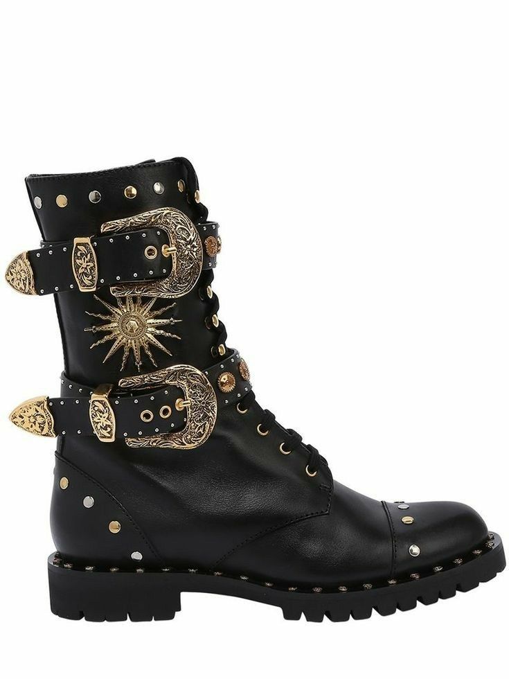 a single black leather hightop combat boot with decorative gold buckles and studs is positioned against a white background. the boot features two prominent goldaccented buckle straps on the upper part of the shaft, along with additional decorative studs, and a star burst symbol. the toe is capped with studs, and the sole is treaded. the boot has a laceup closure system.