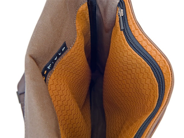 a close up picture of the inside of a brown leather bag. the bag is open and you can see the orange lining and the zipper. the bag is made of high quality leather and has a durable zipper. the bag is perfect for carrying everyday essentials.