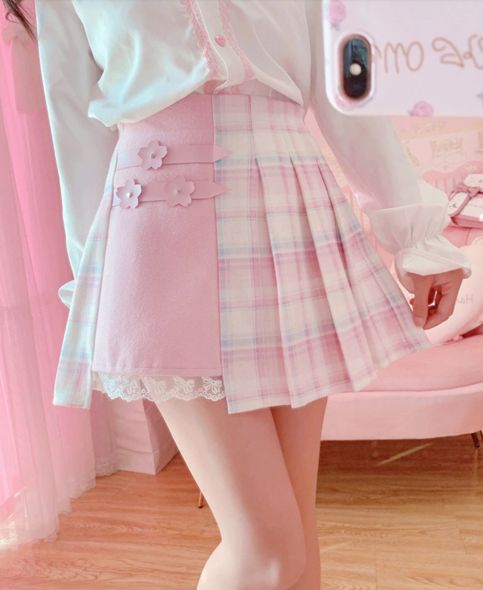 a young woman poses for a mirror selfie in a pastel pink bedroom. she's wearing a white lacetrimmed top and a pink skirt with a pleated plaid pattern on one side and a solid pink panel with decorative bows on the other. the image exudes a soft, feminine, and playful vibe.
