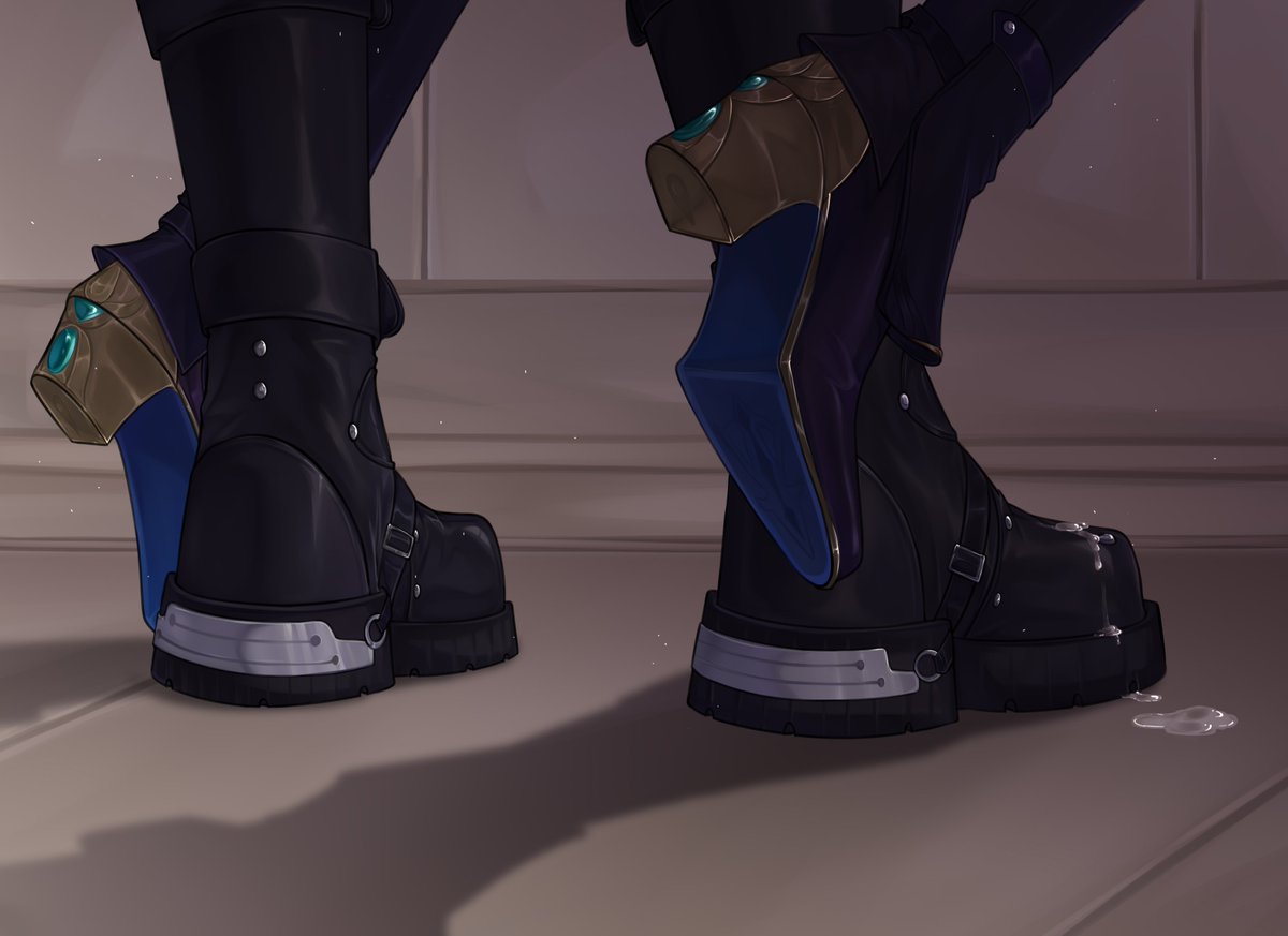 a pair of black leather boots with gold and blue details. the boots have buckles, straps, and laces. the boots are worn by a person and are standing on a floor. there is a puddle of water on the floor. the boots are stylish and fashionable.