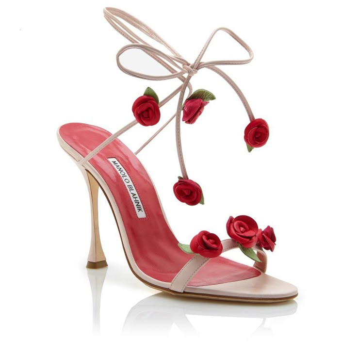 a single manolo blahnik sandal is captured in a welllit studio shot. the shoe is primarily pink and red, featuring a delicate ankle strap with a tied bow. red roses are affixed to the strap and the top of the shoe near the toe, adding an elegant floral detail. the shoe has a slender, high heel and a glossy, reflective sole, enhancing its sophisticated appearance. the background is plain white, which ensures that the focus remains entirely on the shoe.