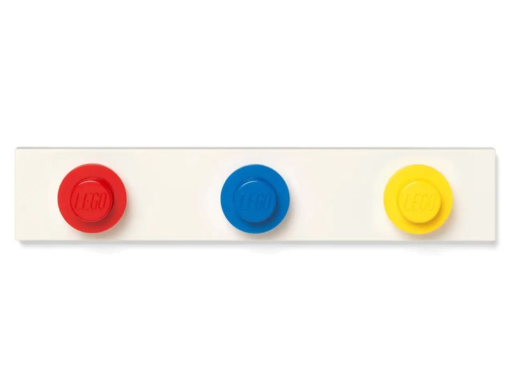a white, wallmounted coat rack with three large, round lego brick buttons in red, blue, and yellow.