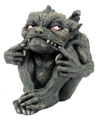 a stone gargoyle statue with a menacing expression is depicted. it is squatting with its arms pulling its mouth open, displaying sharp teeth. the statue has bulging eyes, textured skin, and features suggestive of a demon or monstrous being.