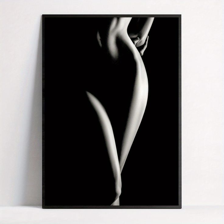 the image is a black and white photograph of a female nude.  the figure is positioned in a threequarter view, with the body angled slightly away from the viewer. the lighting is dramatic, with strong contrasts between light and shadow, creating a chiaroscuro effect that emphasizes the curves and form of the body. the background is pure black, focusing all attention on the subject. the overall mood is sensual and artistic, conveying a sense of elegance and mystery.