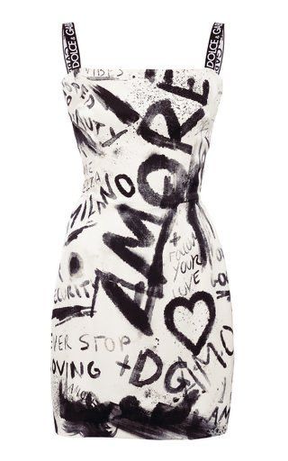 a white sleeveless dress with black graffiti print all over it. the dress has two black straps with "dolce&gabbana" printed on them. it also has a black heart print and the word "love" in black.