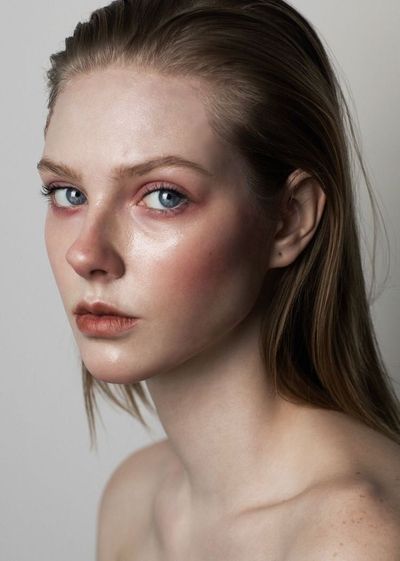 a closeup portrait of a young woman with slickedback, wet blonde hair. she has minimal makeup with a focus on natural beauty and dewy skin. the lighting is soft and diffused, creating a gentle and intimate atmosphere.