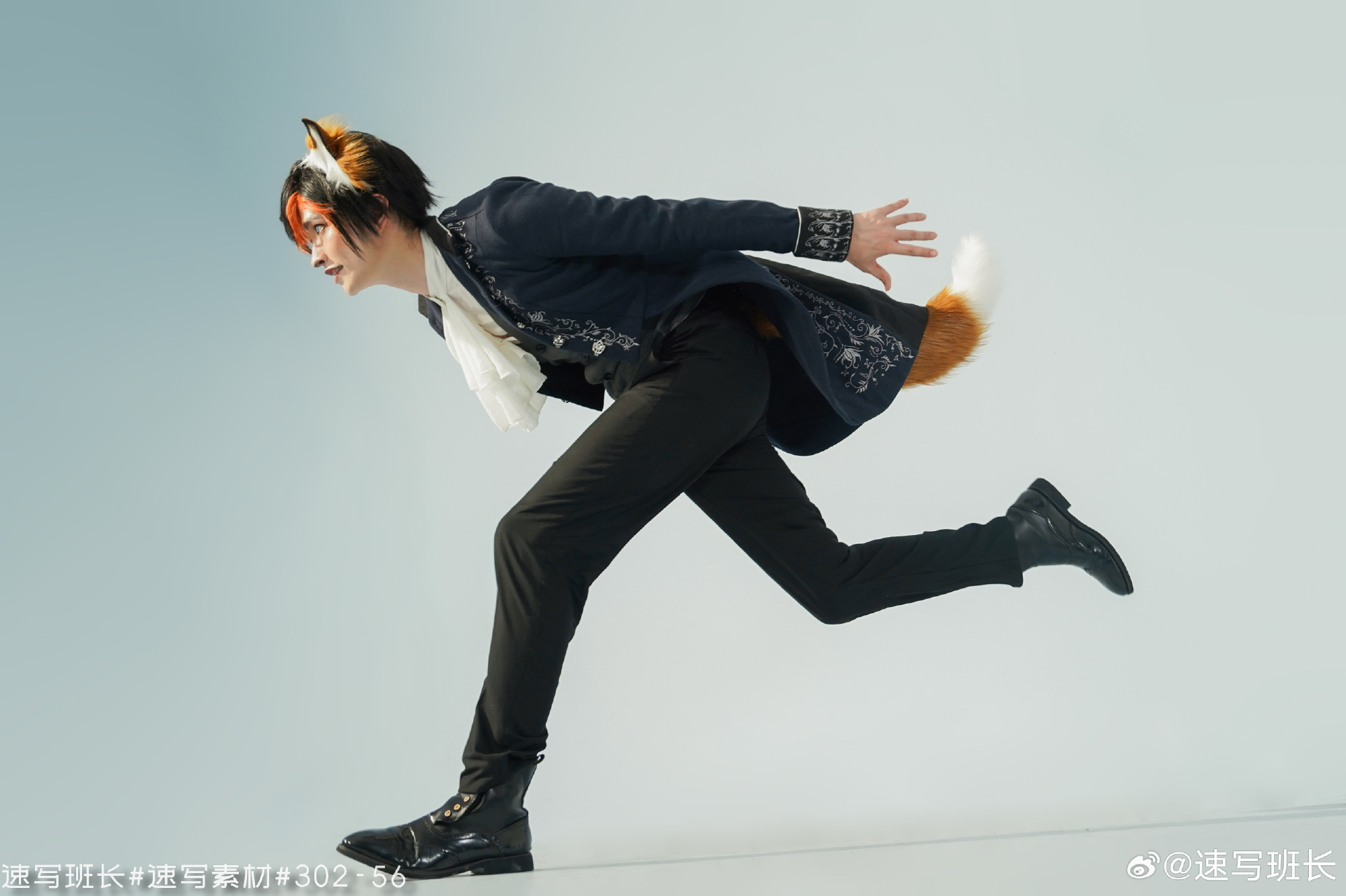 a man in a fox costume is running against a light blue background. he is wearing a navy blue embroidered jacket, white scarf, black pants, black shoes, and a red fox tail and ears.