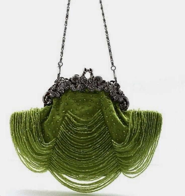 a green vintage beaded handbag with a beaded fringe and chain strap is displayed. the bag has an ornate clasp.