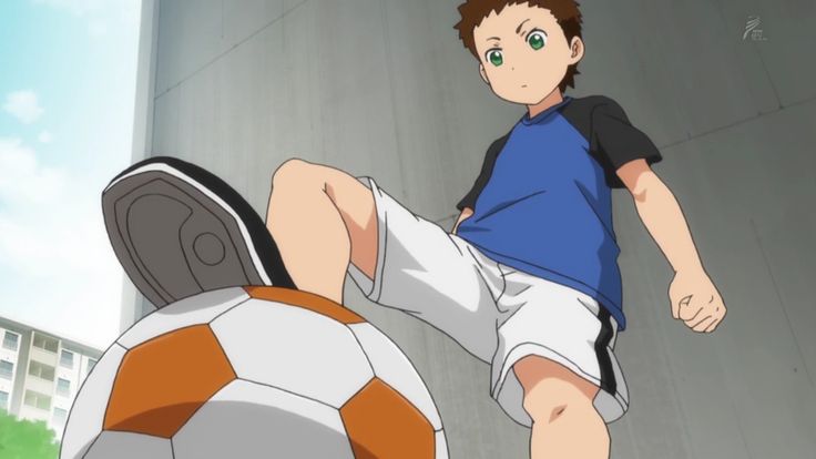 this image is an anime illustration of a boy wearing a white shirt and blue shorts kicking a soccer ball. the boy's foot is in the air, and his right hand is clenched in a fist. the boy is smiling and appears to be happy about kicking the ball.