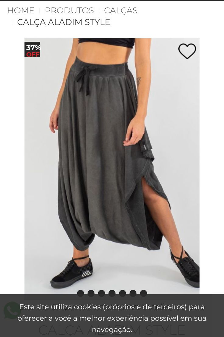a woman models a pair of dark gray, haremstyle pants with a drawstring waist, pockets, and slits. she is also wearing black sneakers. the pants are advertised as "calça aladim style" and are 37% off.