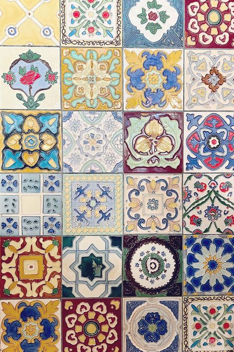 a closeup shot of a wall covered in a mosaic of colorful square tiles.  each tile features a unique design, ranging from floral patterns to geometric shapes, all in vibrant hues. the overall effect is a rich, textured, and visually striking surface. the tiles appear to be ceramic or pottery, possibly handmade or handcrafted, exhibiting a traditional or vintage aesthetic.  the image is a detailed and intricate display of varied repeating patterns.