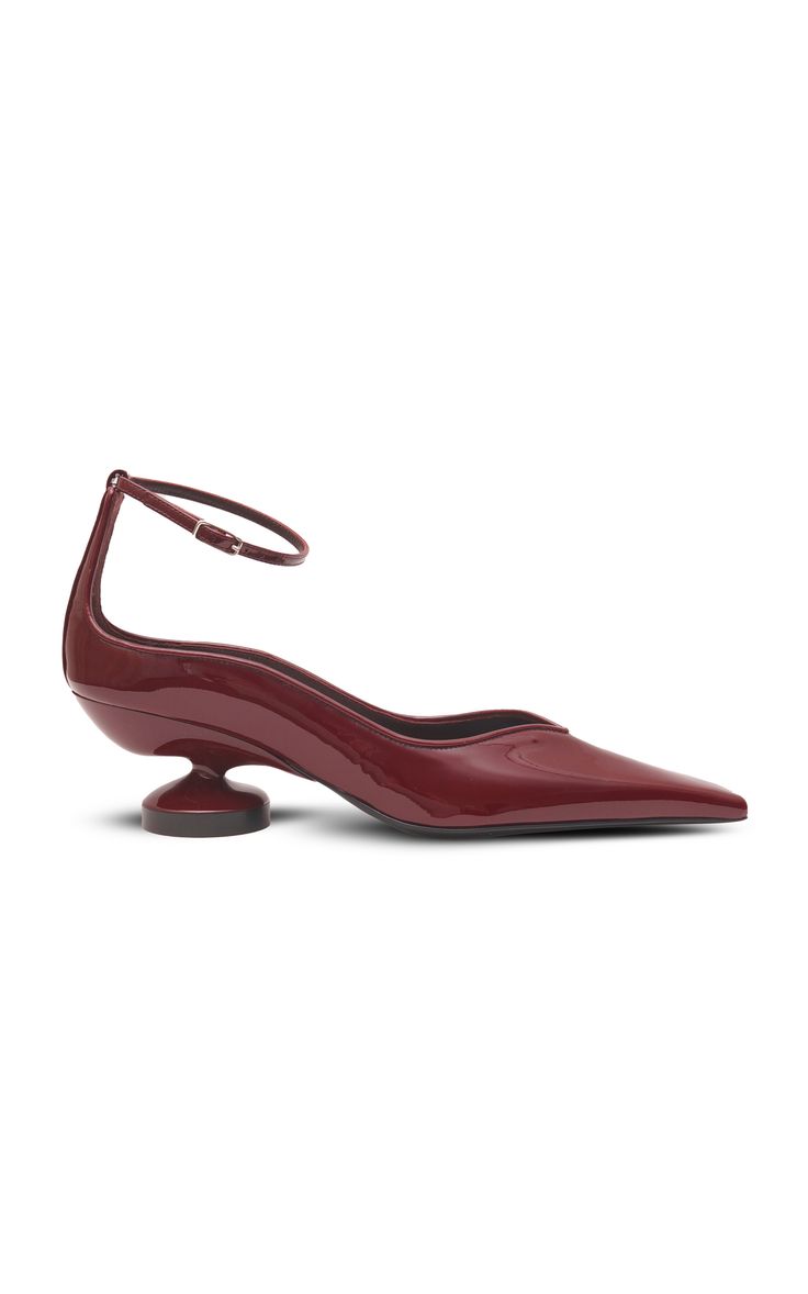 a pair of red patent leather women's shoes with a pointy toe and an ankle strap. the shoes have a single sole with a rounded heel.