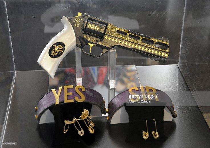 the image showcases a gun with "hate" and "love" inscribed on it and two "yes sir" headbands displayed on black stands.