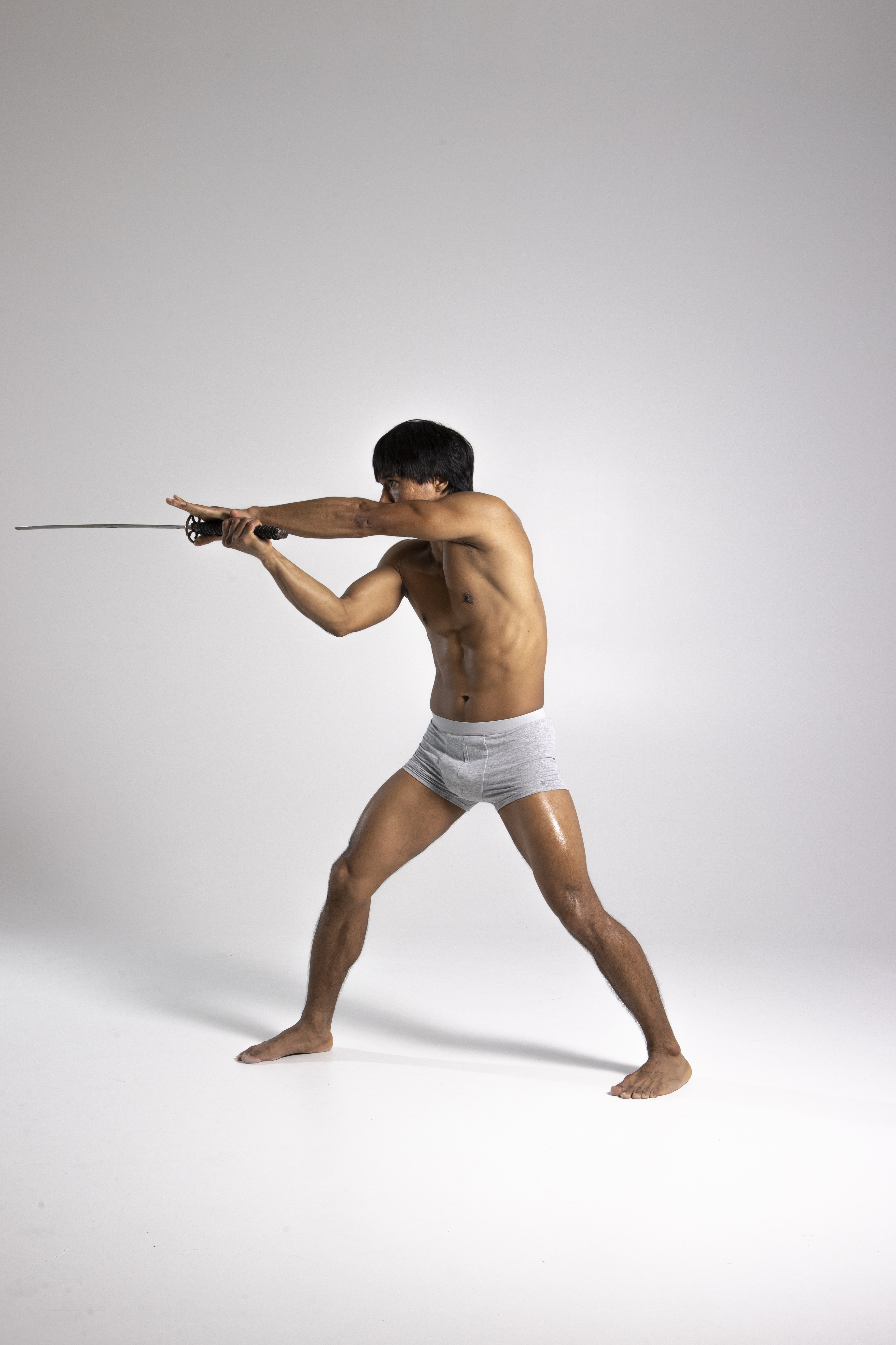 a shirtless man wearing underwear holds a katana sword with both hands, posing against a white background. he has an athletic build and is barefoot.