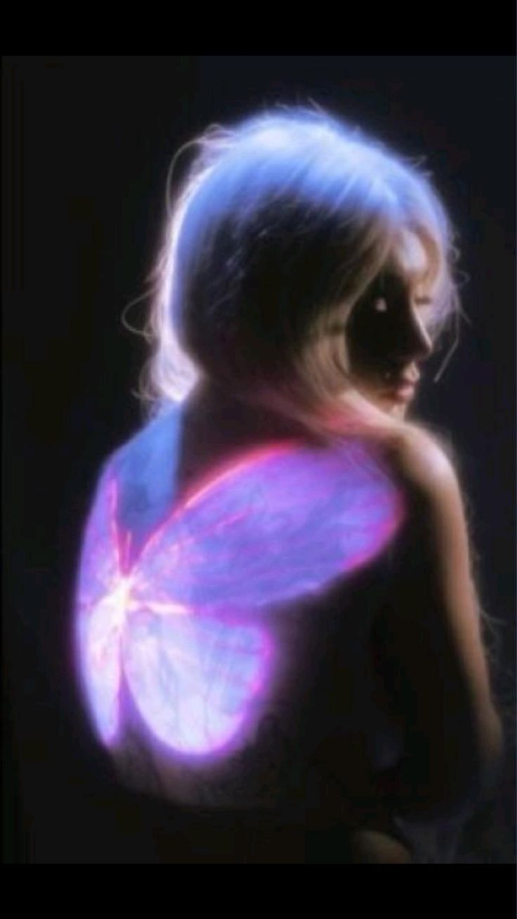 a young woman with long, flowing blonde hair appears ethereal as she is illuminated by glowing, purple, angel wings. the image evokes a sense of magic and wonder, with a dreamy and mystical atmosphere. the woman's delicate features and the soft glow of the wings create a captivating scene that feels both enchanting and otherworldly.