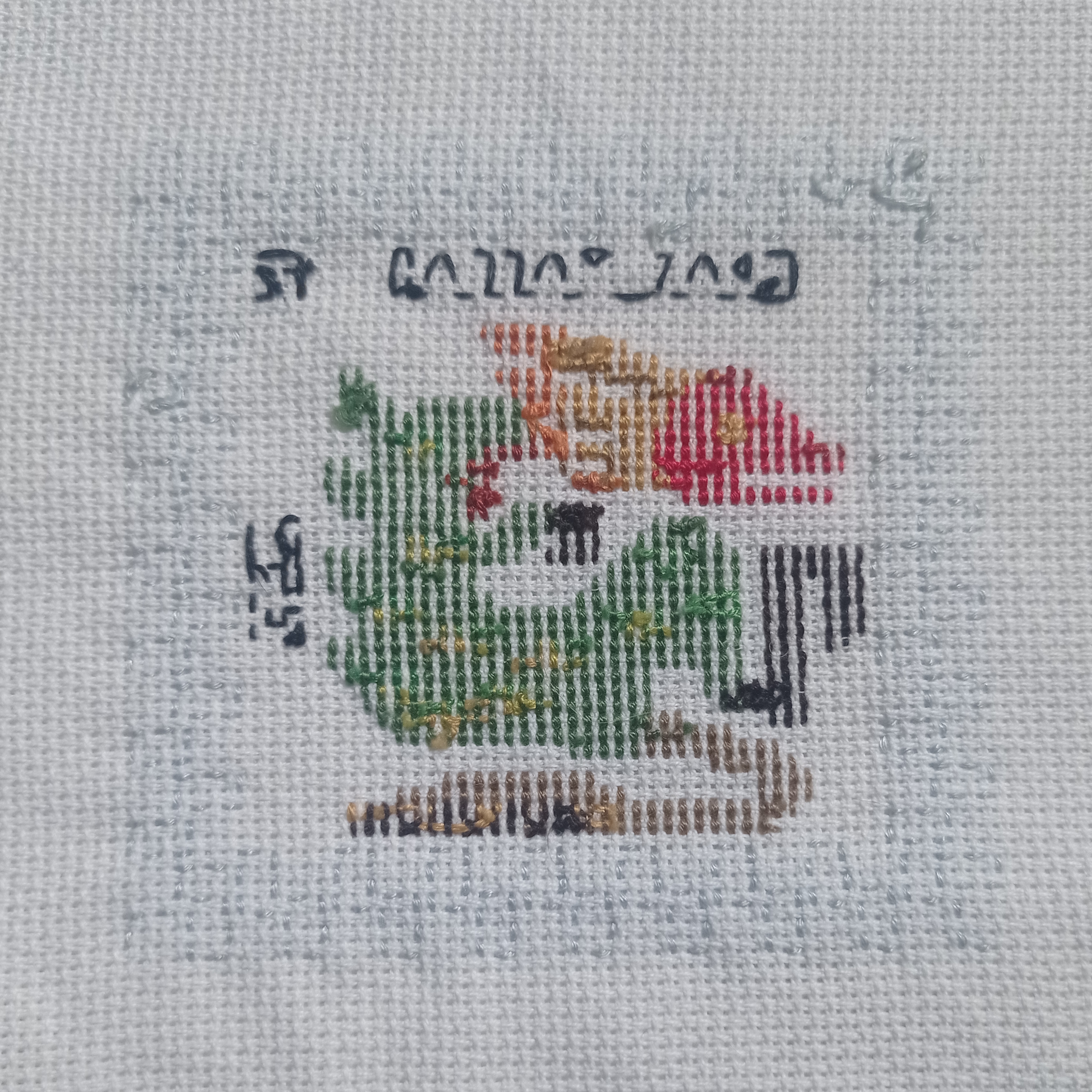 the image shows an inprogress crossstitch embroidery project of a dragon. the dragon is primarily worked in green, orange, red, and brown thread on a beige aida cloth. the top of the project shows the top of the design, with some of the pattern printed on the fabric.