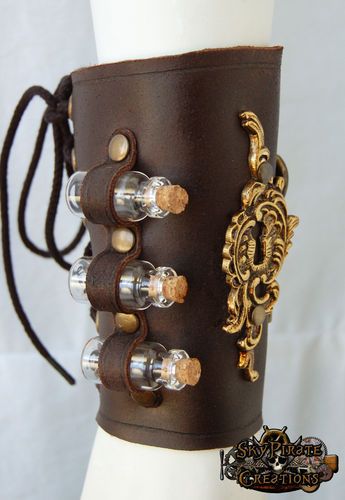 a closeup view of a brown leather steampunk bracelet adorned with four glass vials capped with cork stoppers. the vials are held in place by leather straps and metal rivets. a decorative goldcolored metal piece with intricate details enhances the steampunk aesthetic. the bracelet is displayed on a white mannequin arm.