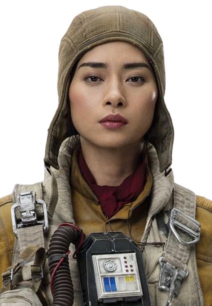 a woman in a brown cap with gray fabric around her neck, wearing a tan jacket with a red scarf and a brown strap with a buckle. she is looking straight into the camera.  the background is out of focus, but you can see what appears to be a piece of gear in the foreground.