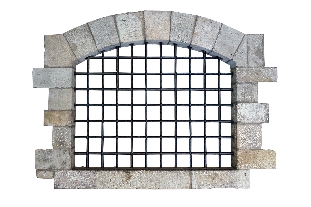 a barred window with a stone frame against a black background. the window is arched at the top and has a grid of metal bars filling the opening. the stone frame is made of rectangular blocks.