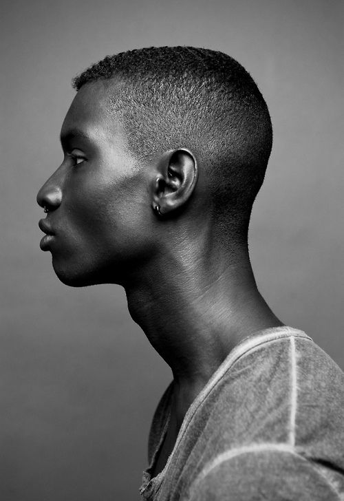 a black and white profile portrait of a man with short hair, a nose ring, and an earring. he is wearing a tshirt, and his neck is visible.