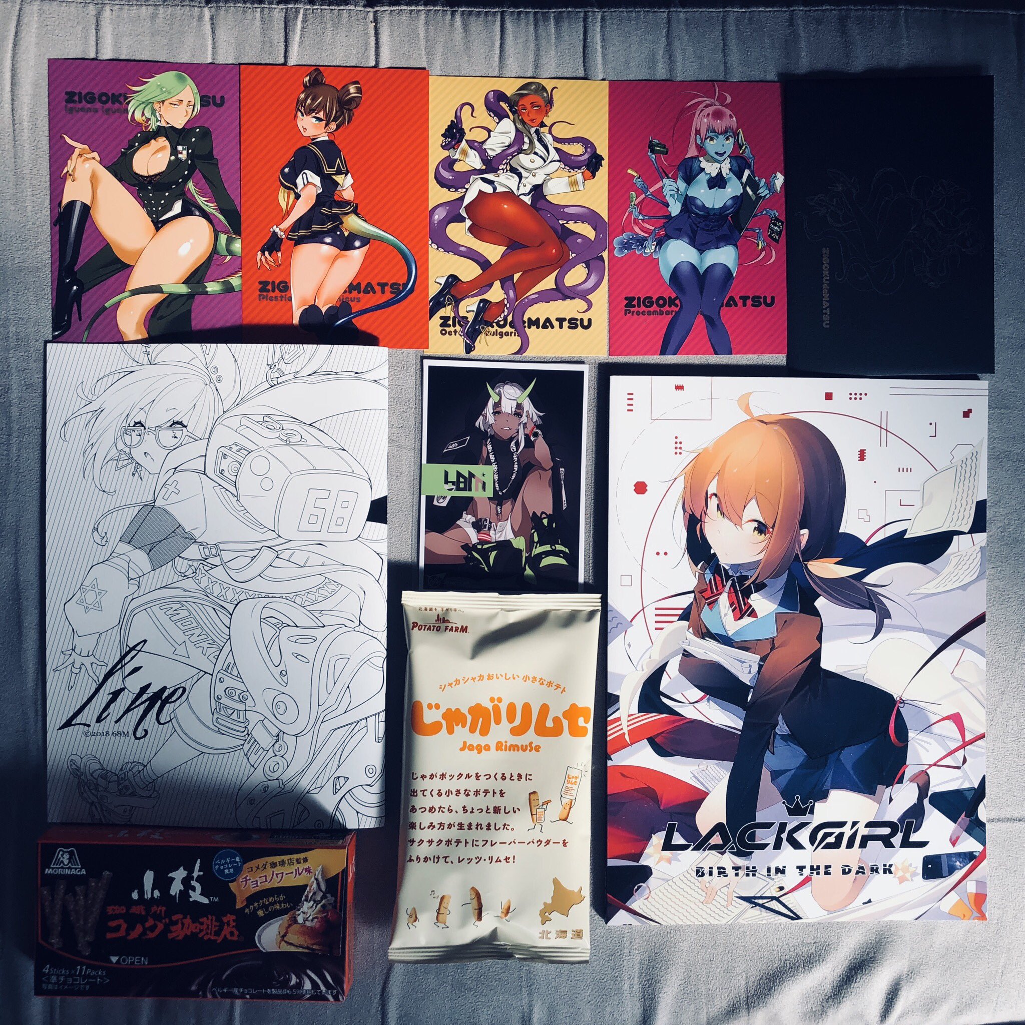 the image shows a topdown view of a collection of anime merchandise, likely laid out on a bed. the merchandise includes several posters or art prints featuring female anime characters in dynamic poses and outfits, often with weaponry. there's also a black sketchbook or artbook, a bag of potato snacks with japanese writing, and a box of what appears to be japanese candy. the overall aesthetic leans towards a cyberpunk or futuristic theme with bold colors and sleek character designs.