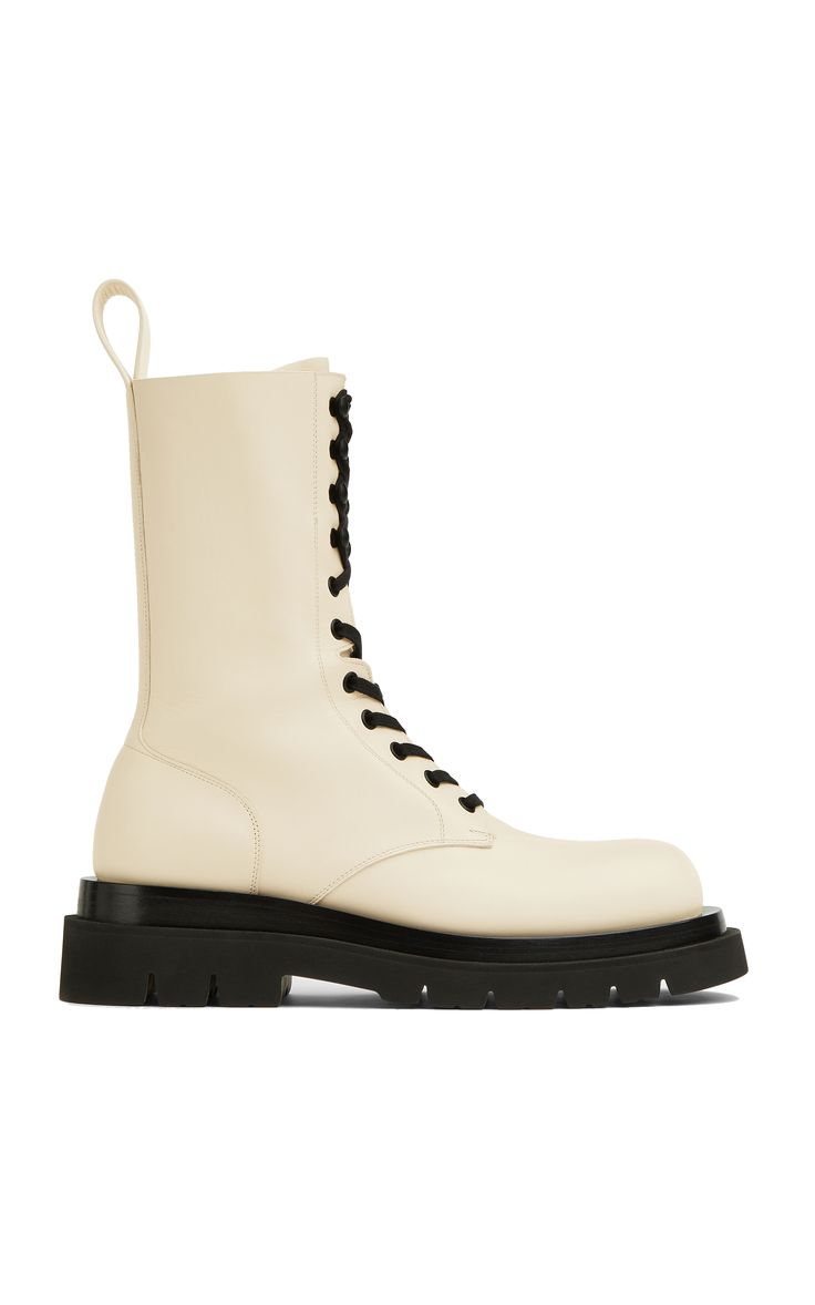 a pair of women's creamcolored laceup boots are presented in a studio shot against a white background. the boots are made of leather with a chunky platform sole and are styled with black laces. the boots are slightly angled, showing the side profile. the overall aesthetic is minimalist and chic.