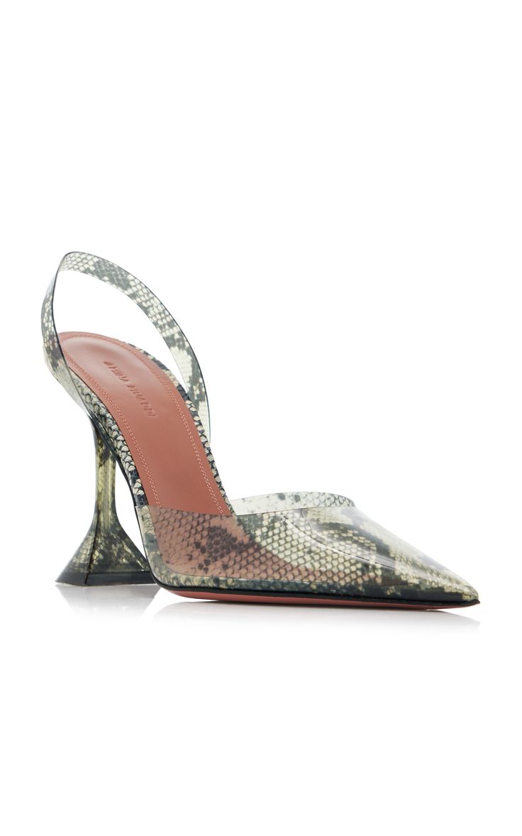a pair of women's amina muaddi slingback high heels are shown. the shoes are transparent with a snake print pattern and have a unique sculpted heel. the shoes are presented on a white background.