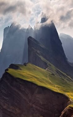 a majestic mountain range with steep cliffs and peaks, shrouded in mist and clouds. the image captures the raw beauty and grandeur of nature, showcasing the power and resilience of the natural world. the dramatic lighting and the sense of vastness create a feeling of awe and wonder.
