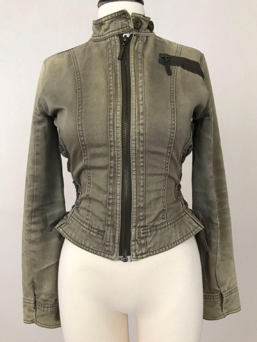 a closeup shot of a woman's olive green denim jacket with a zipper closure. the jacket is a cropped style and features a fitted silhouette.