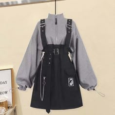 a black and grey pinafore dress with a black skirt and a grey jumper. the dress has a black belt and straps, and the jumper has a zipper up the front. the dress is loosefitting and casual, and it would be perfect for a day of shopping or running errands. the dress is also stylish and trendy, and it would be perfect for a night out with friends. the dress is comfy and chic, and it would be perfect for any occasion. the dress is oversized and loose, and it would be perfect for a casual look. the dress is made from a soft and comfortable material, and it would be perfect for any season. the dress is available in a variety of sizes, and it would be perfect for any body type.